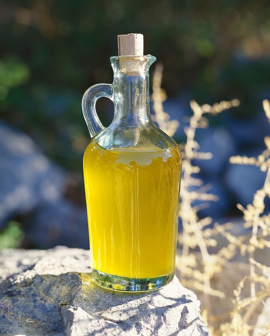 A carafe of olive oil on a stone