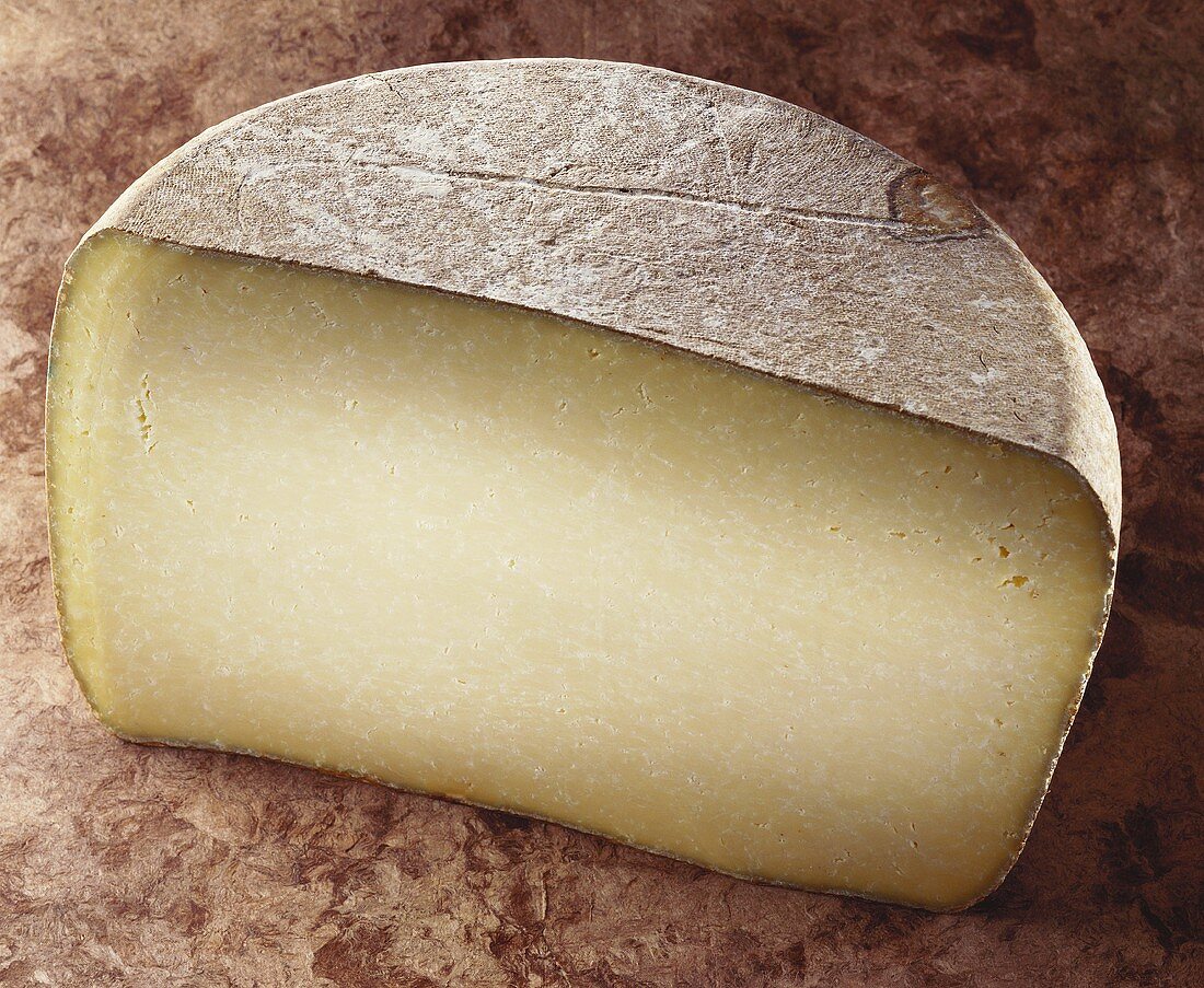 Cantal, a French hard cheese on brown background