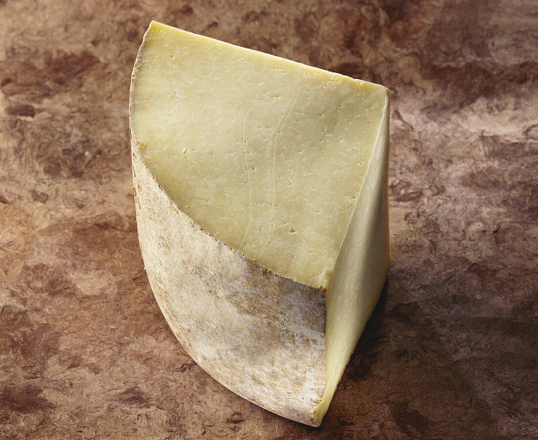 Laguiole, a French hard cheese, on brown background