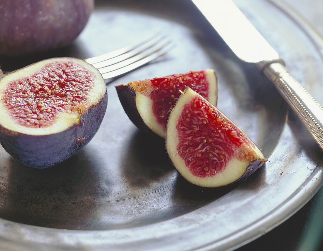 Figs, cut into, on a tin plate with cutlery