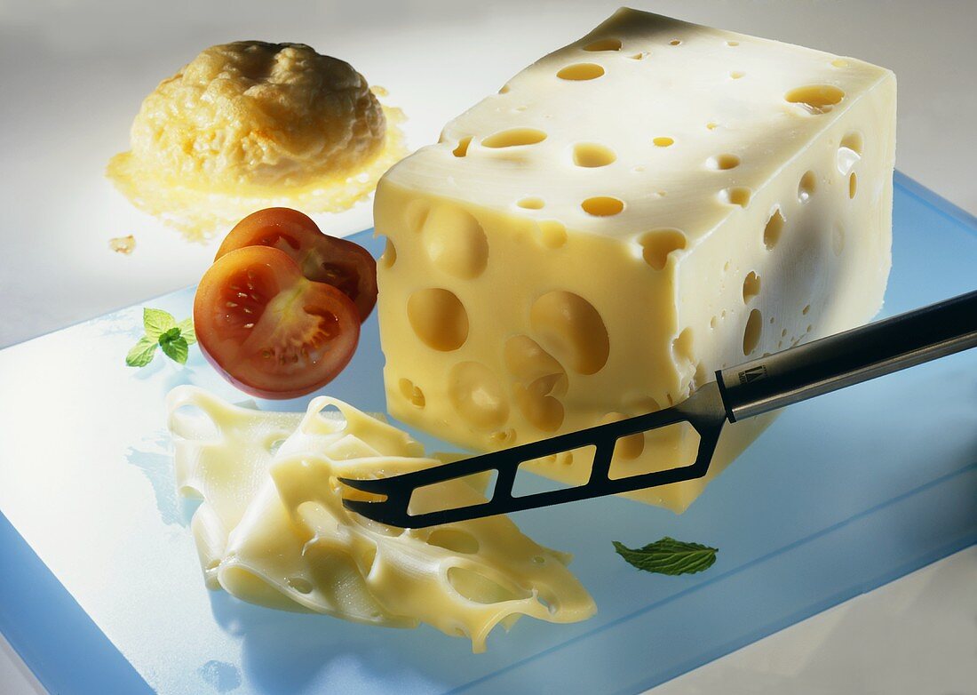 Emmental cheese with cheese knife, two tomato halves & roll
