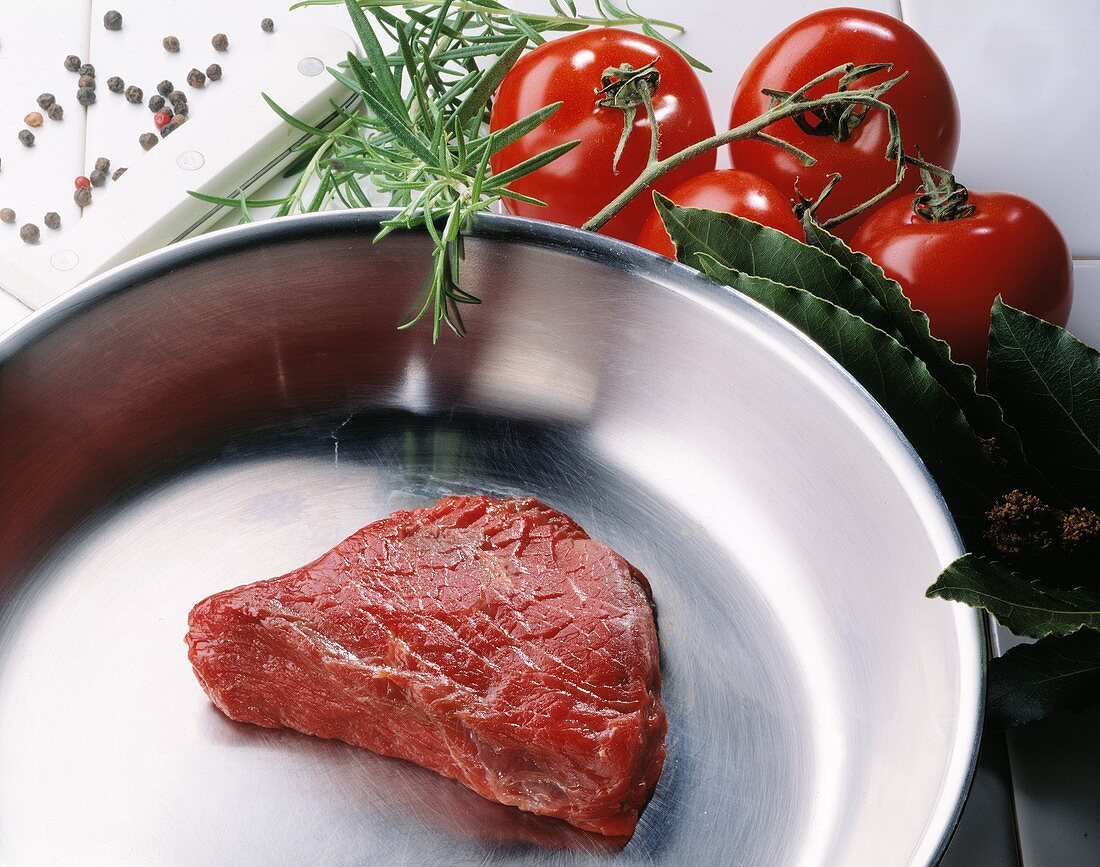 Fillet steak in a pan; tomatoes, herbs, spices