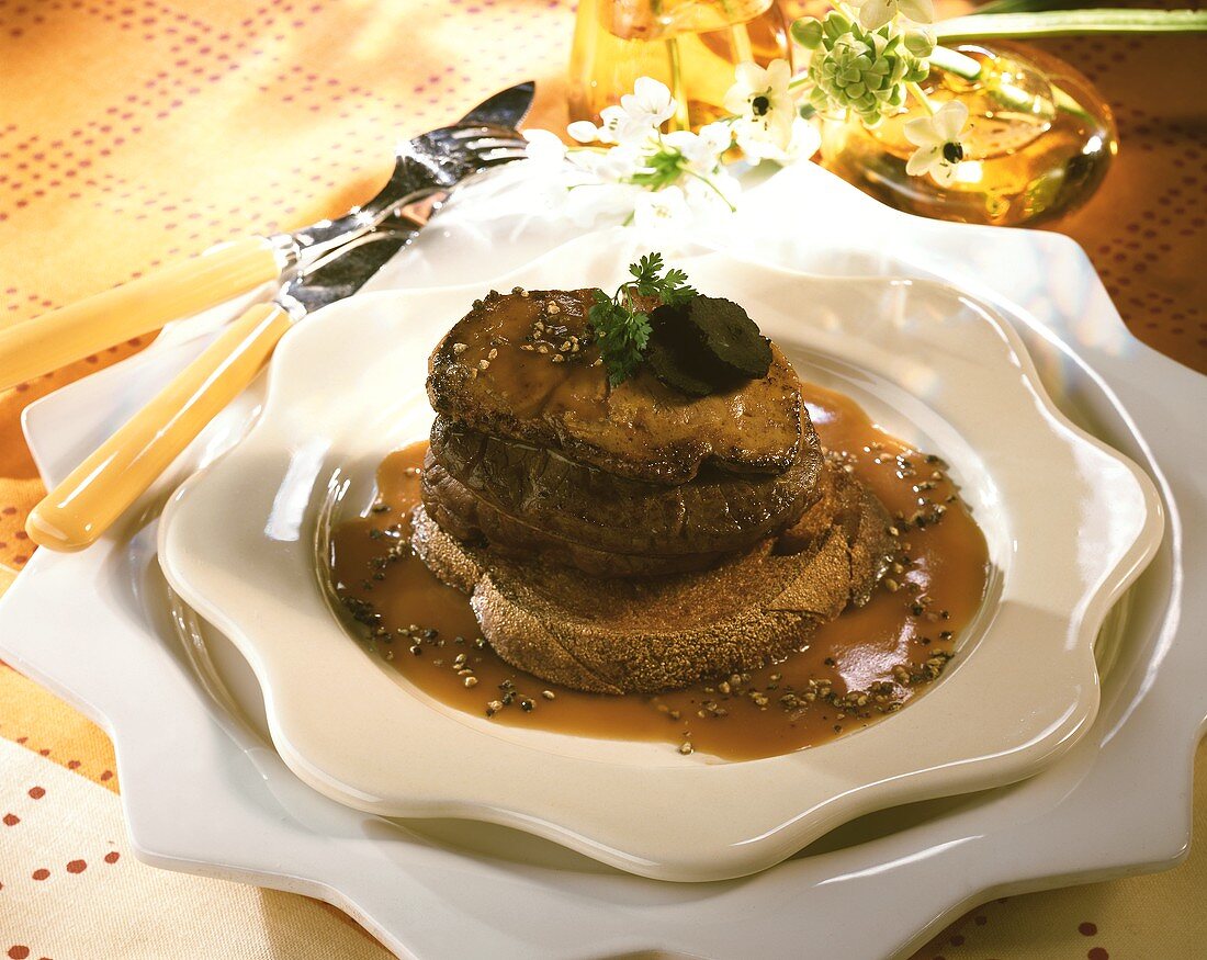 Beef fillet with truffles on slice of bread in pepper sauce