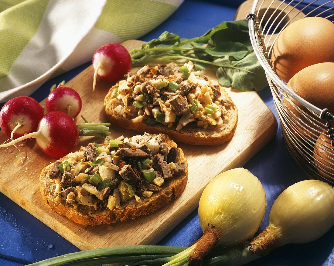 Open sandwiches with chopped liver & eggs on chopping board