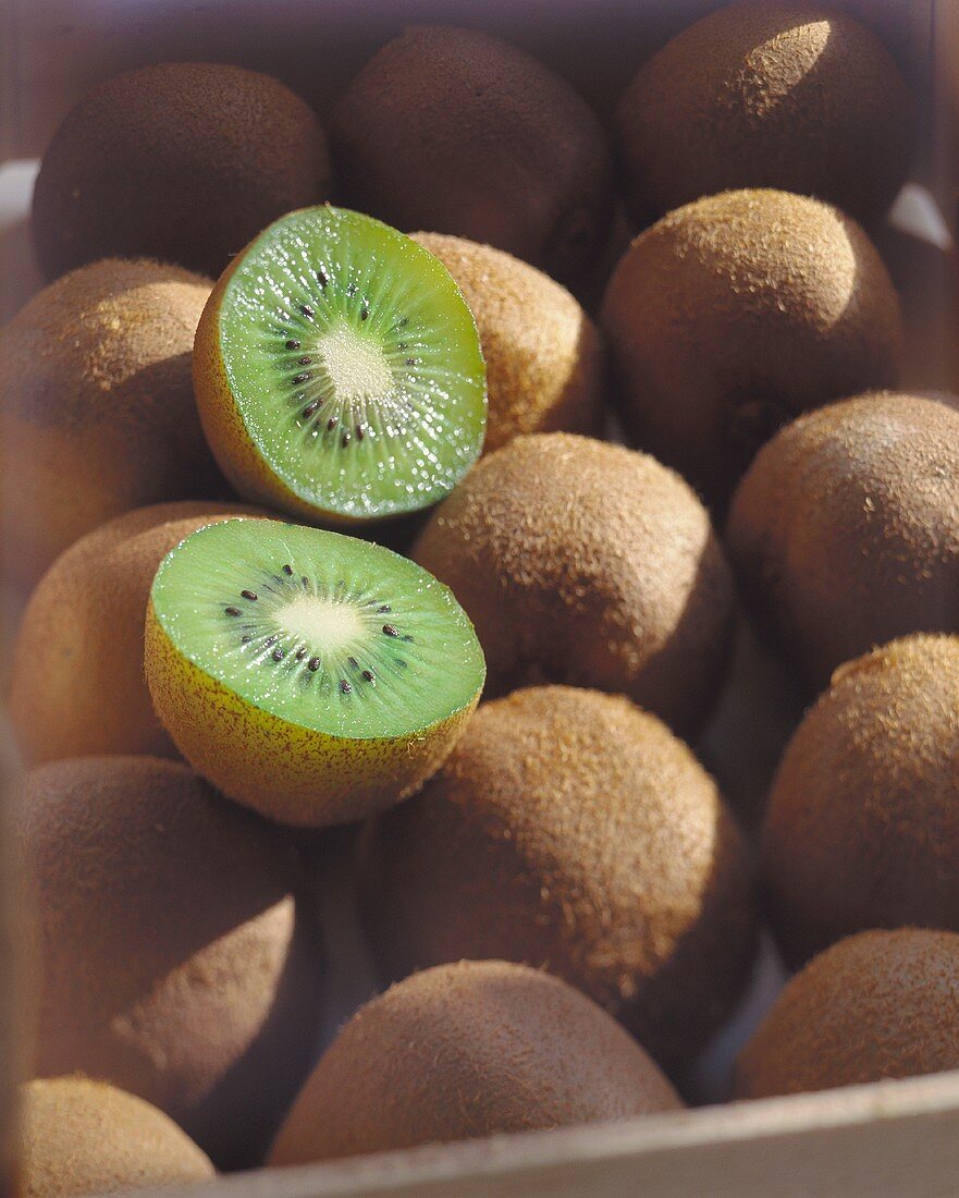 Kiwis, eine davon halbiert, in einer Kiste