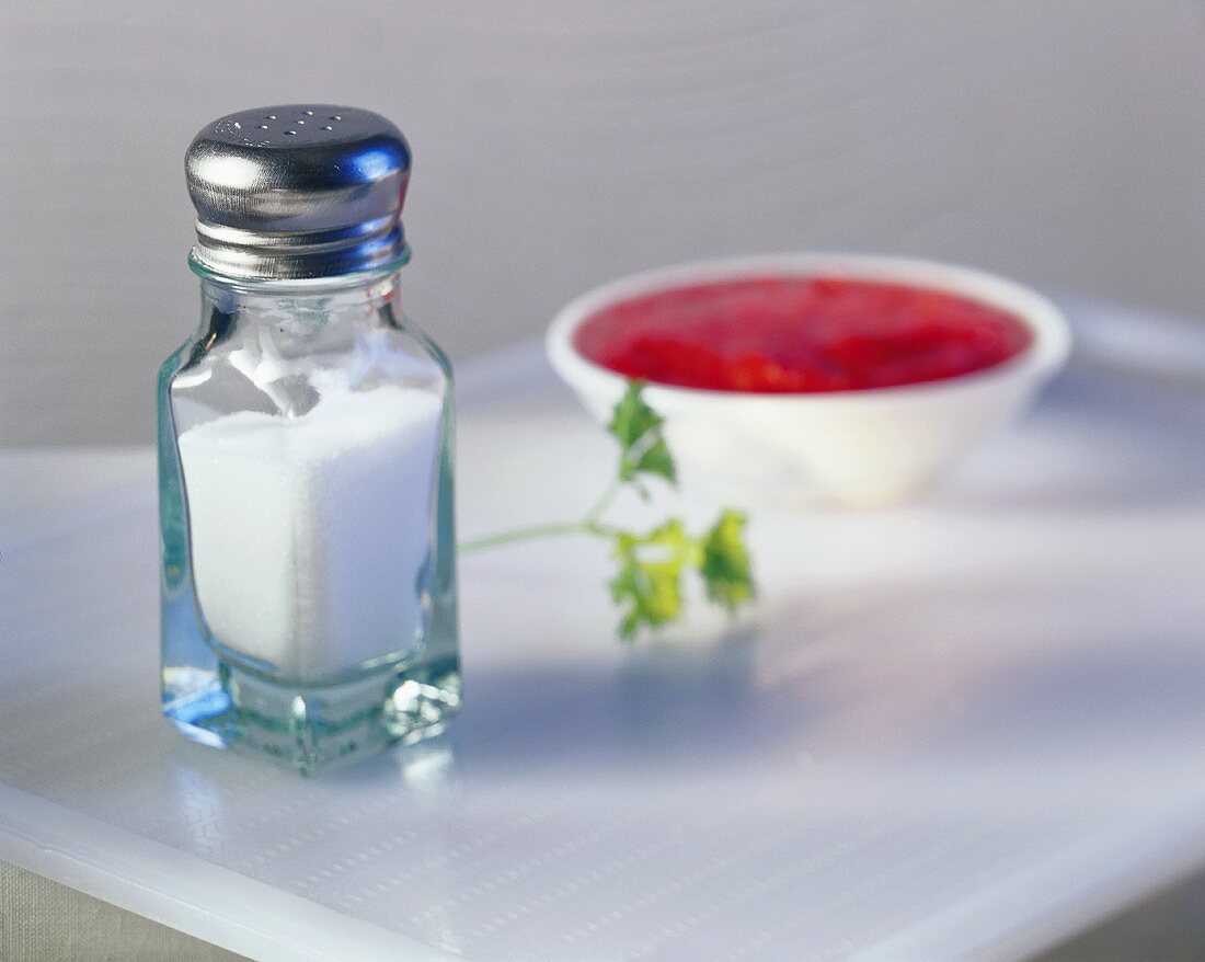 Salz im Salzstreuer, dahinter Tomatensauce im Schälchen