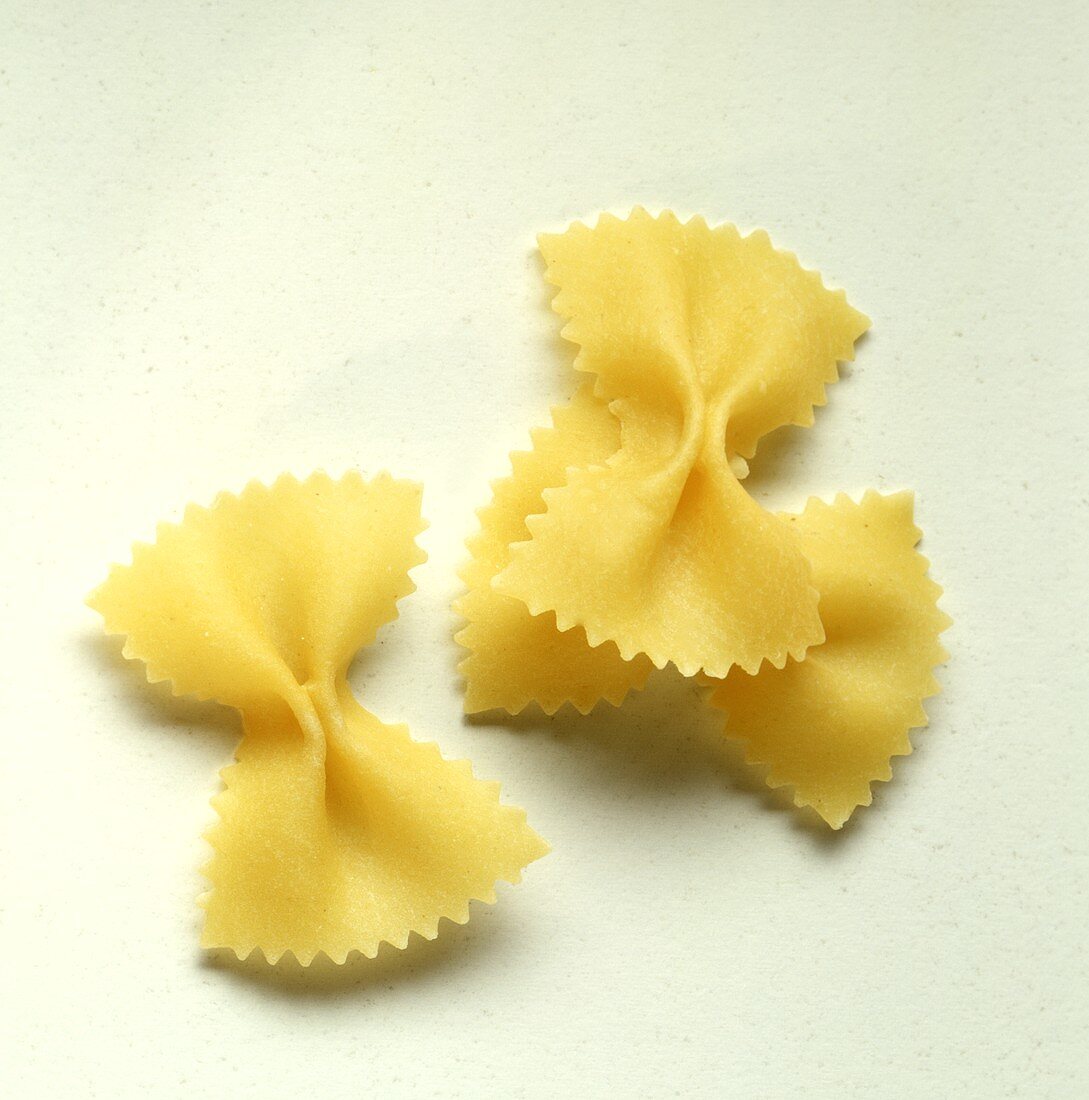Three farfalle (pasta bows) on white background