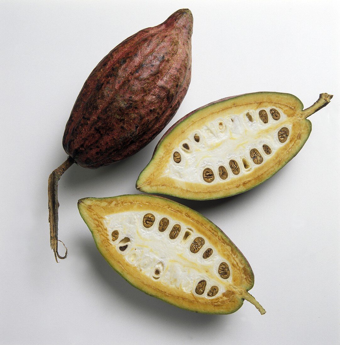 Cocoa beans, one halved, on a white background