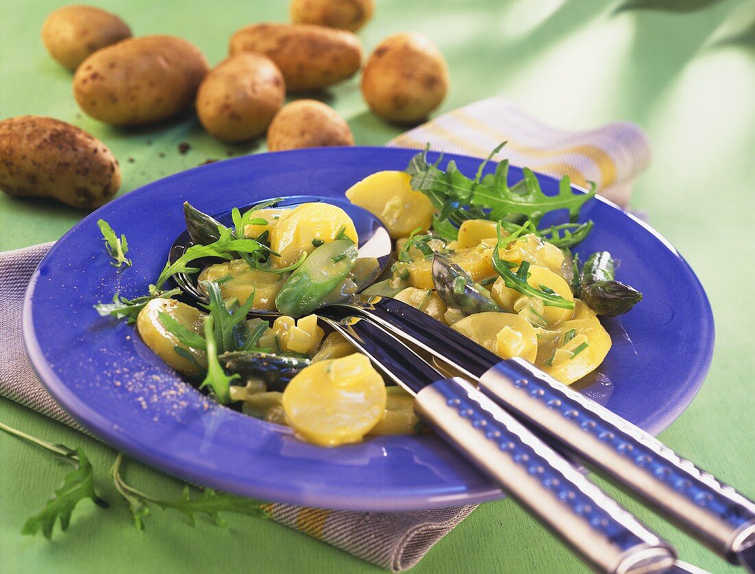 Kartoffel-Spargel-Salat mit Rucola auf blauem Teller
