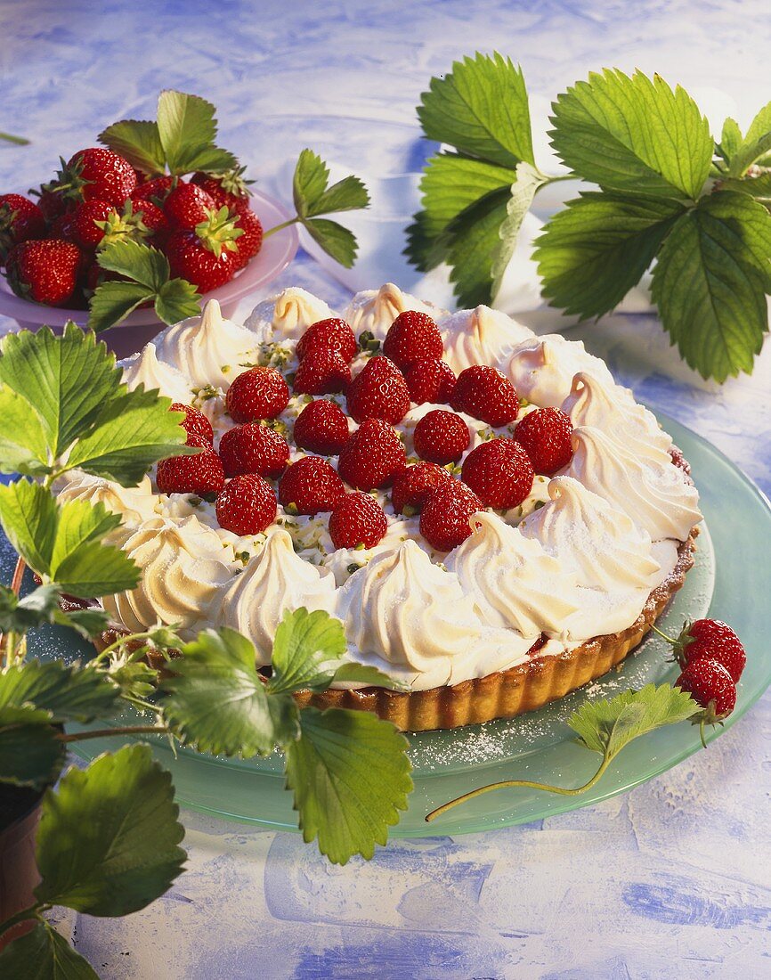 Strawberry meringue tart surrounded by strawberry leaves