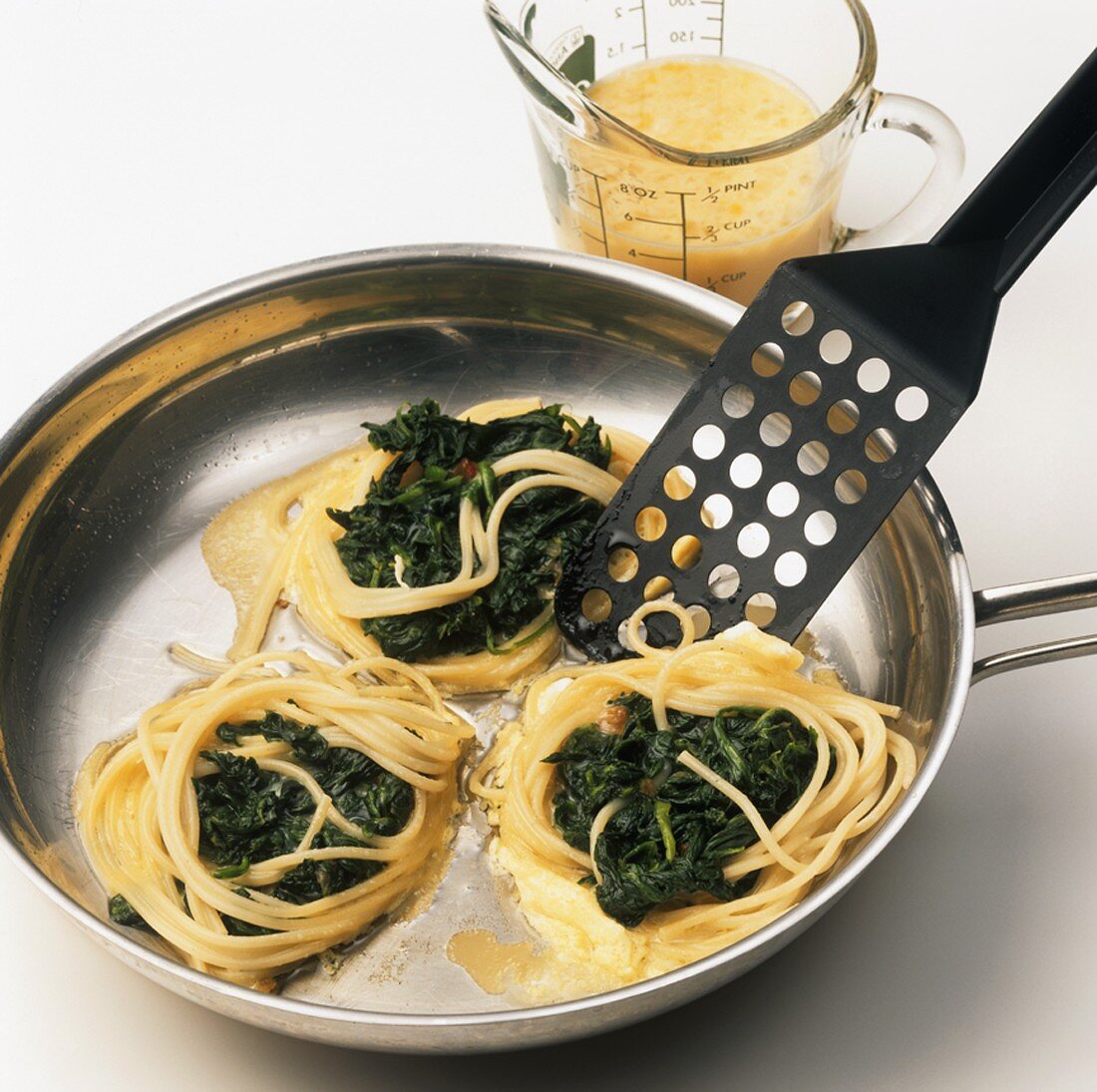 Making fried spaghetti nests with spinach
