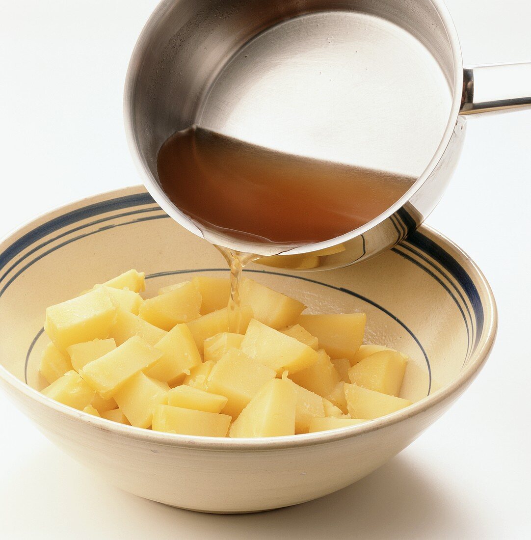 Pouring stock over potatoes