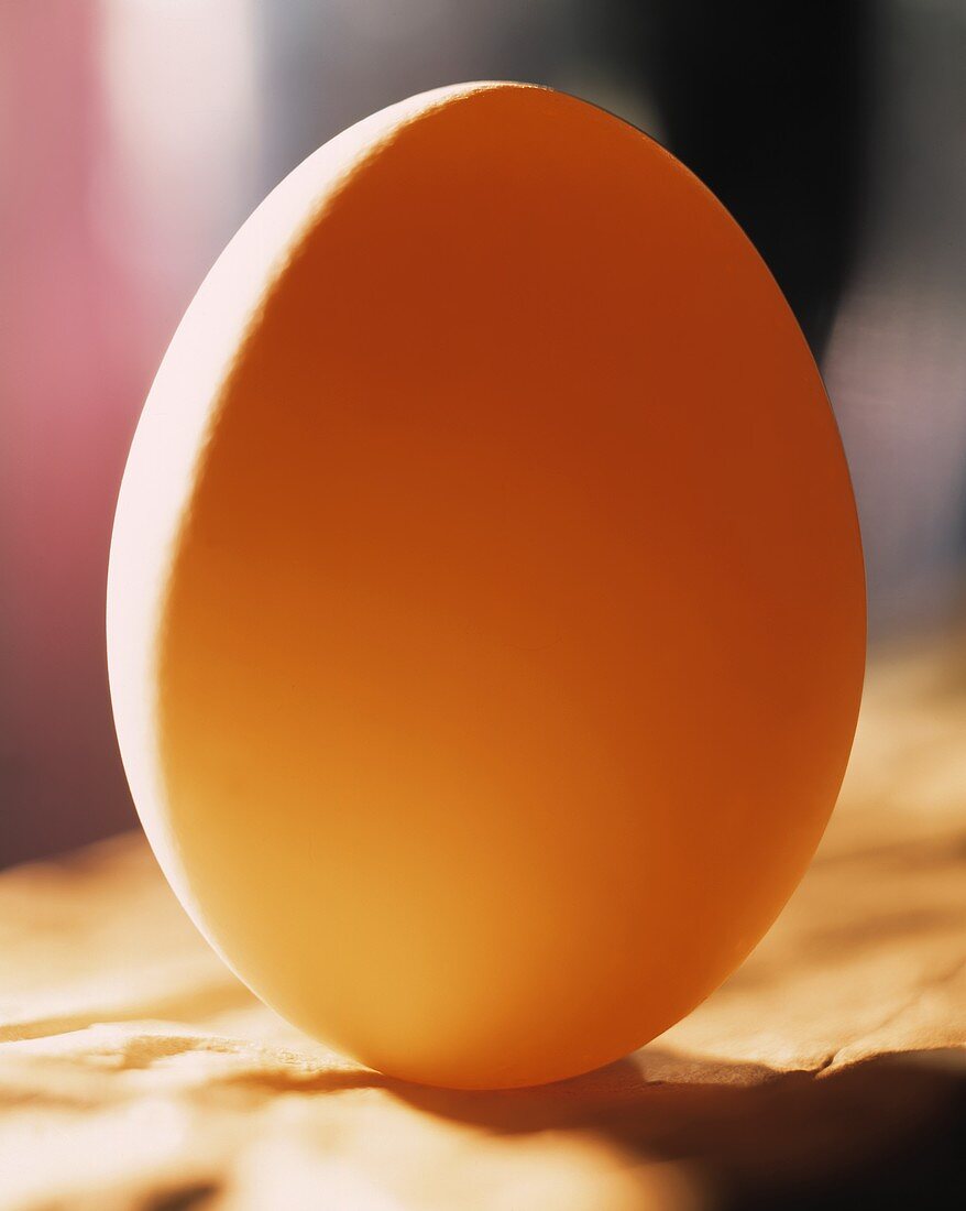 Ein aufgestelltes weisses Ei, orange beleuchtet