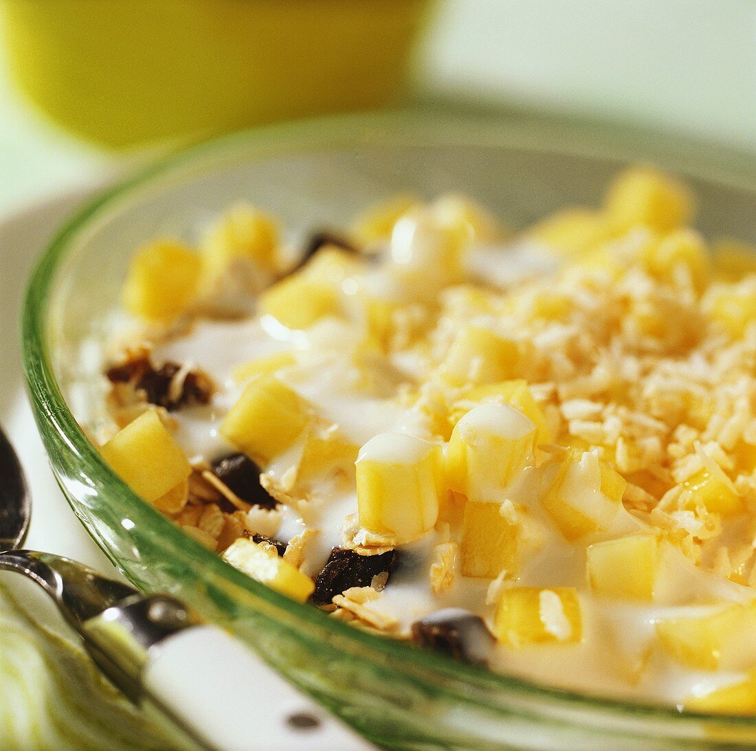 Mango muesli with grated coconut in glass bowl