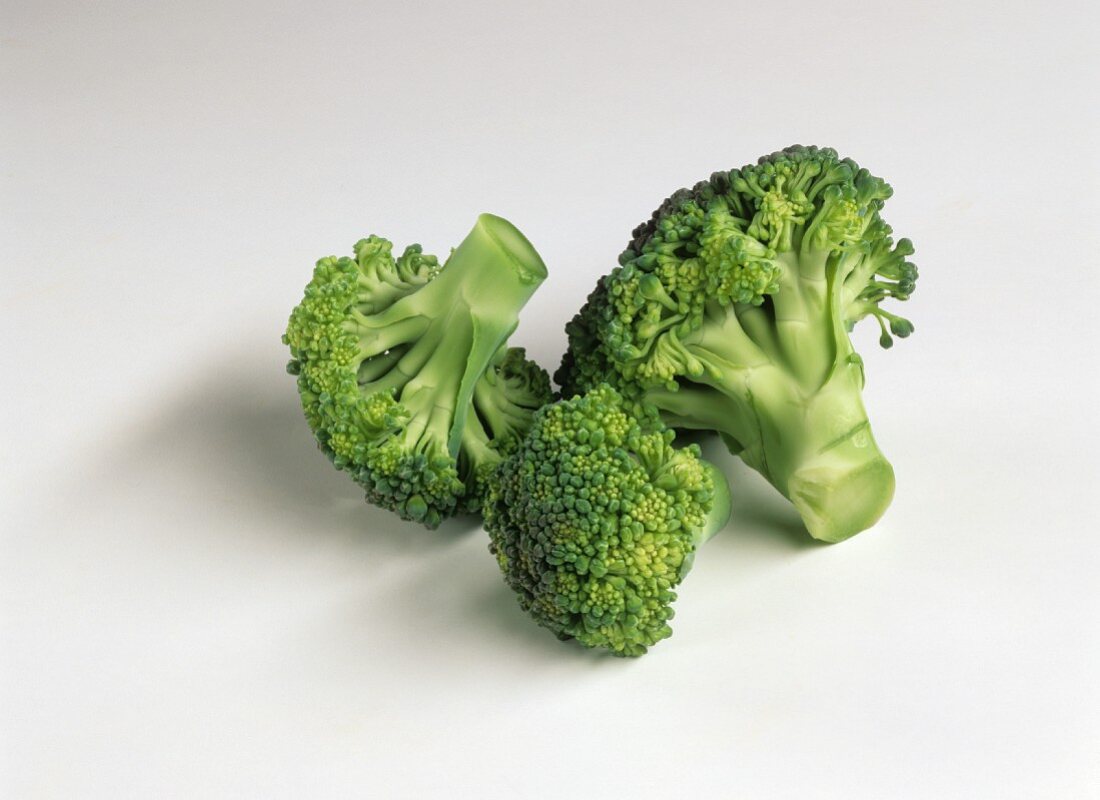 Three broccoli florets on white background