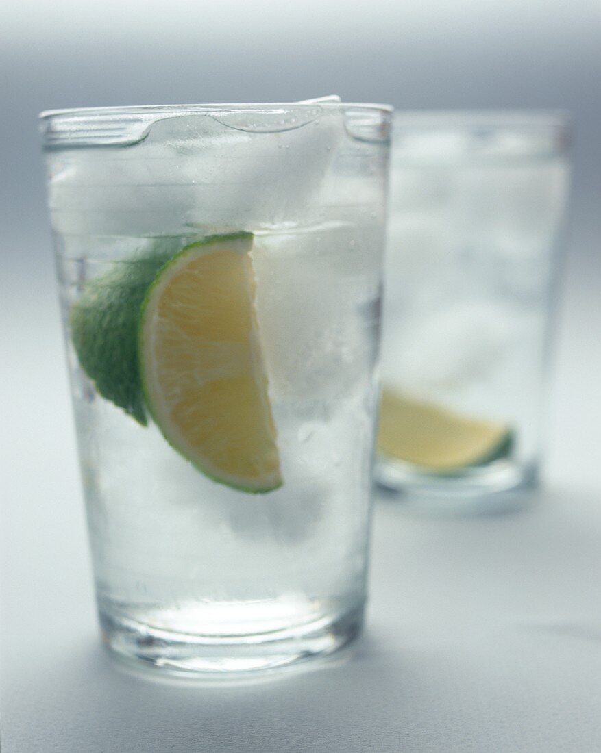 Two gin and tonics with lime slices and ice cubes