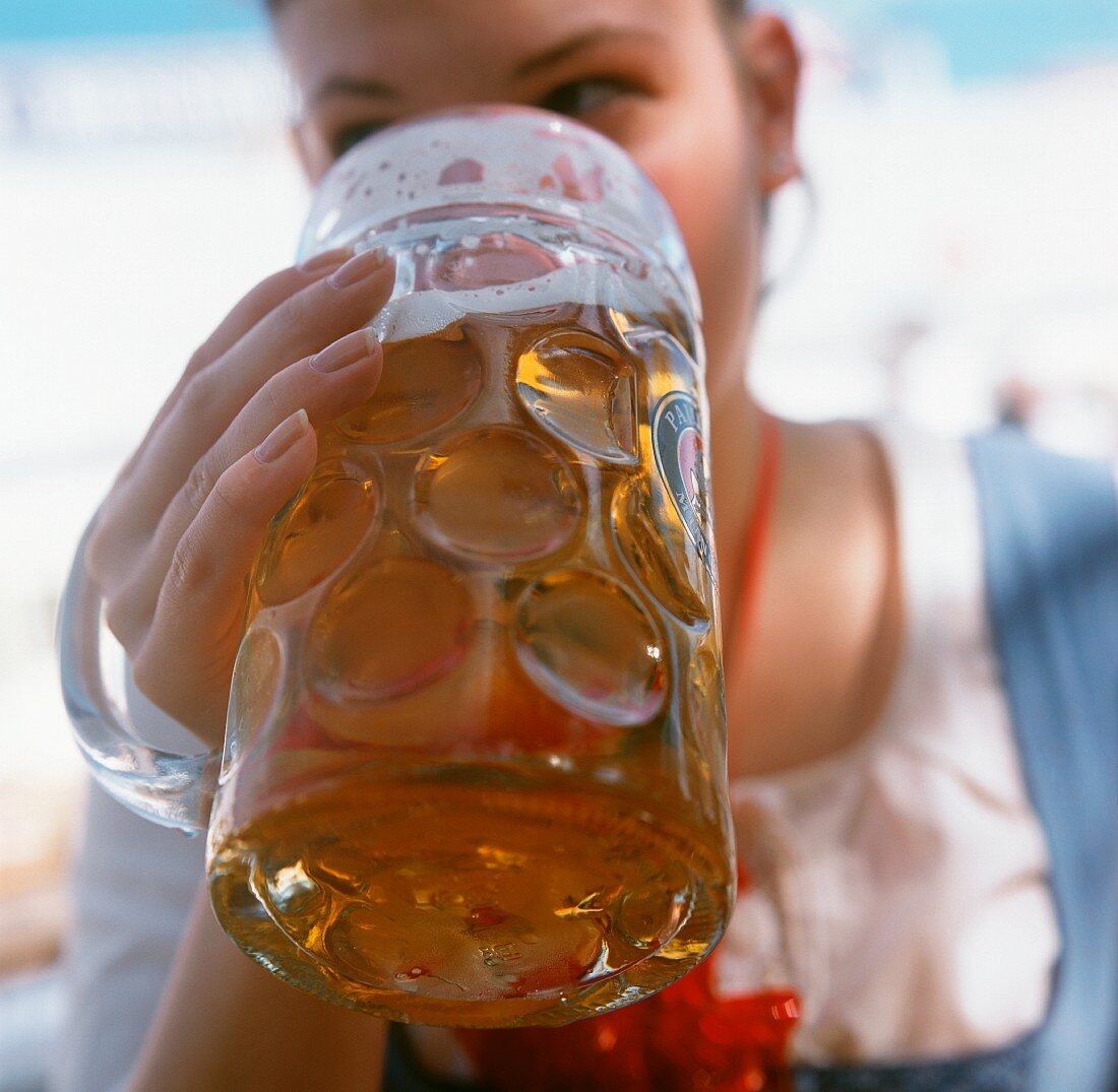 Junge Frau trinkt Bier am Oktoberfest
