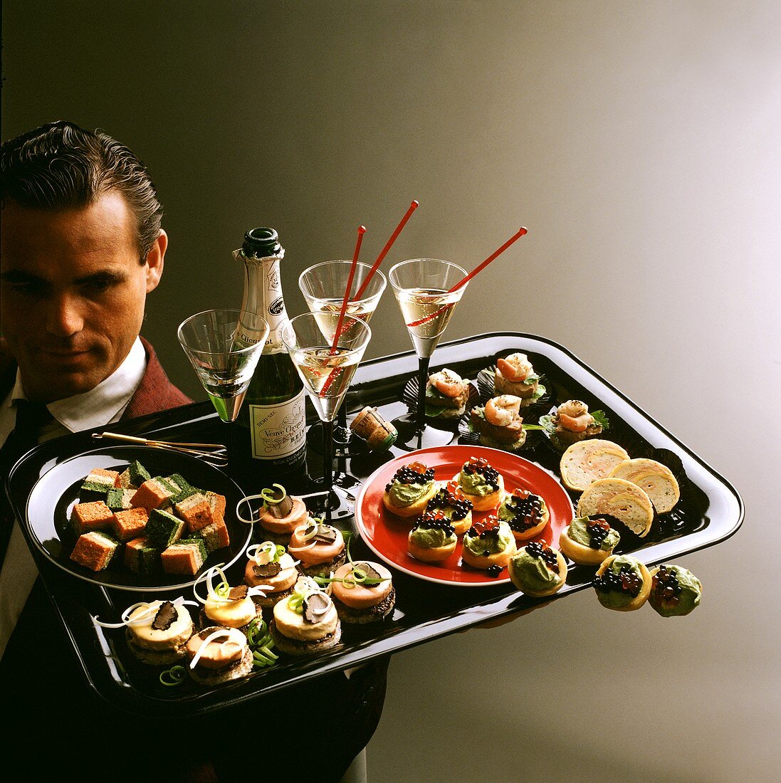 Waiter serving elegant snacks and champagne on a tray
