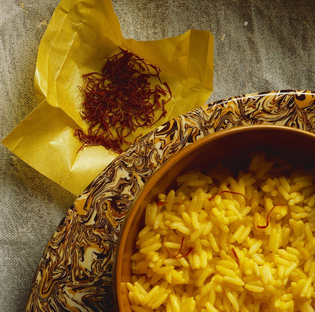 Saffron rice in a bowl with saffron strands on paper