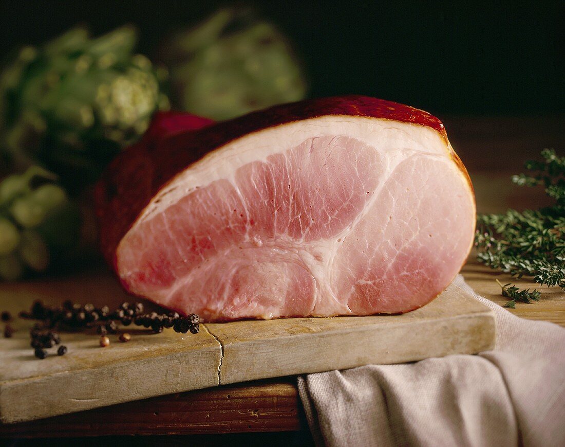 Ham on an old wooden chopping board with juniper berries