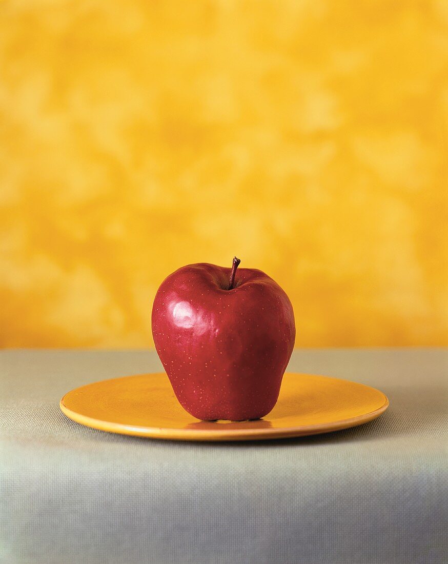 Ein roter Apfel auf gelbem Teller