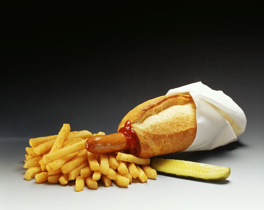 Hot Dog mit Serviette, Pommes frites, Ketchup und Gewürzgurke