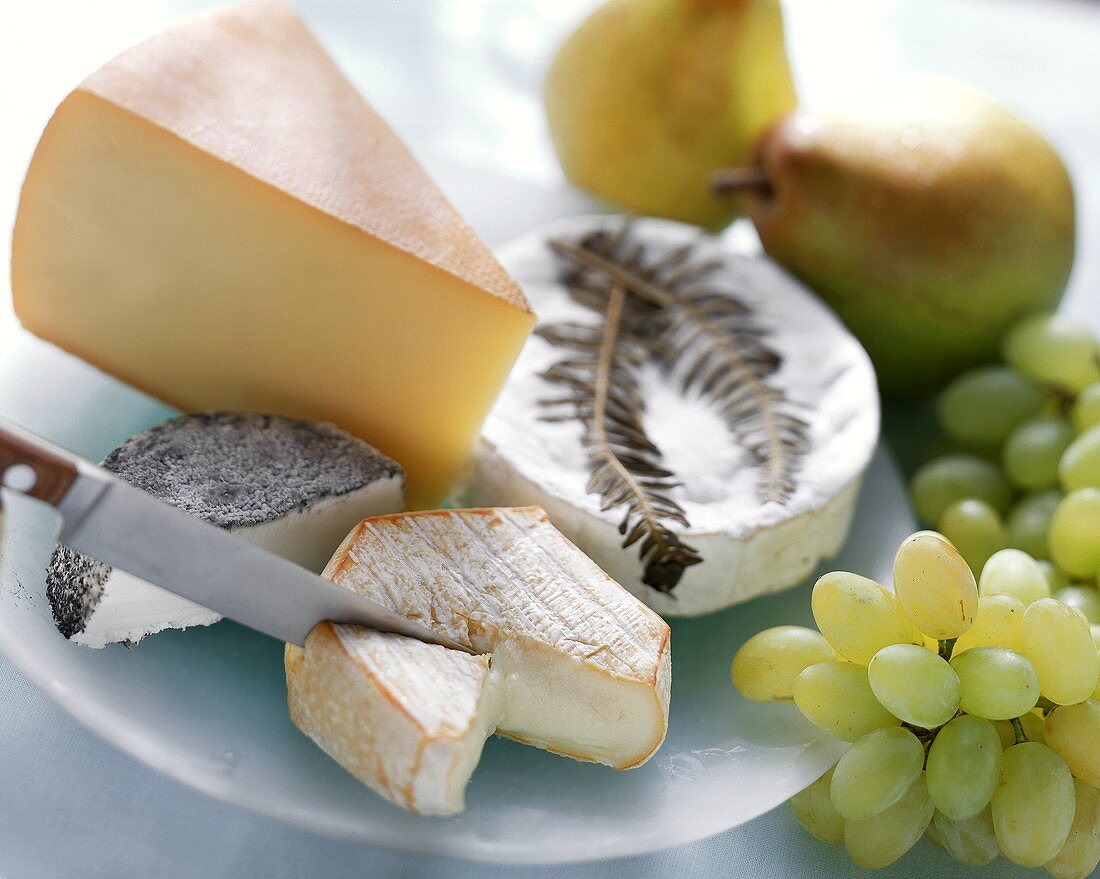 Various types of cheese with pears, grapes and knife
