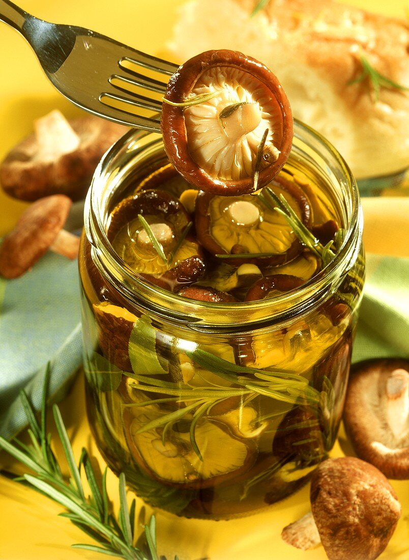 Shiitake mushrooms in rosemary oil in glass & on fork