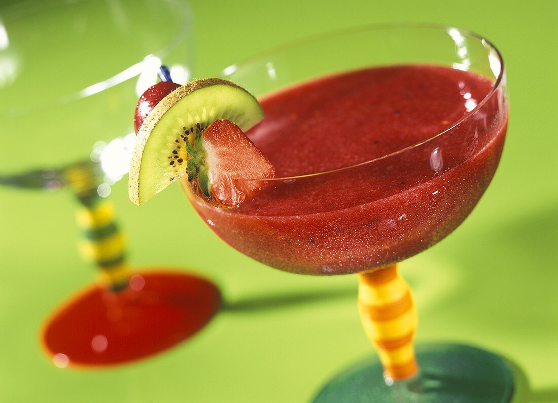 Strawberry and raspberry smoothie in glass with fruit kebab