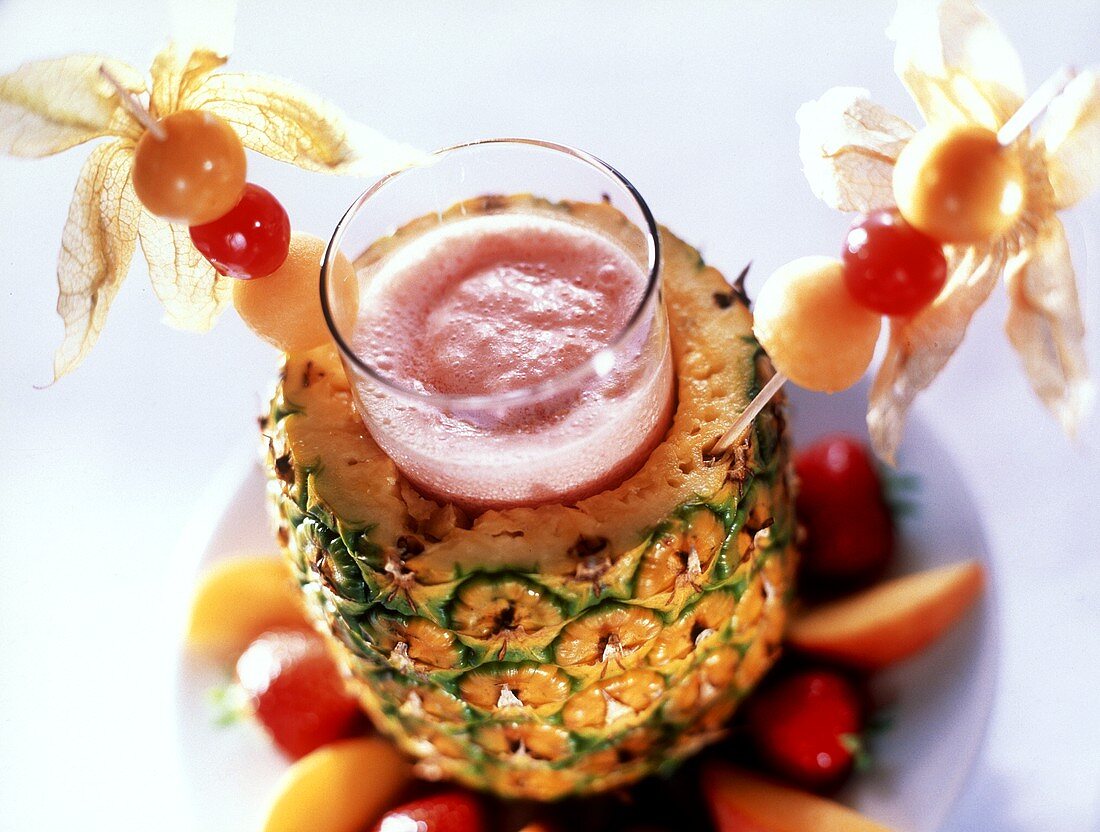 Fruity strawberry cocktail in glass in hollowed-out pineapple