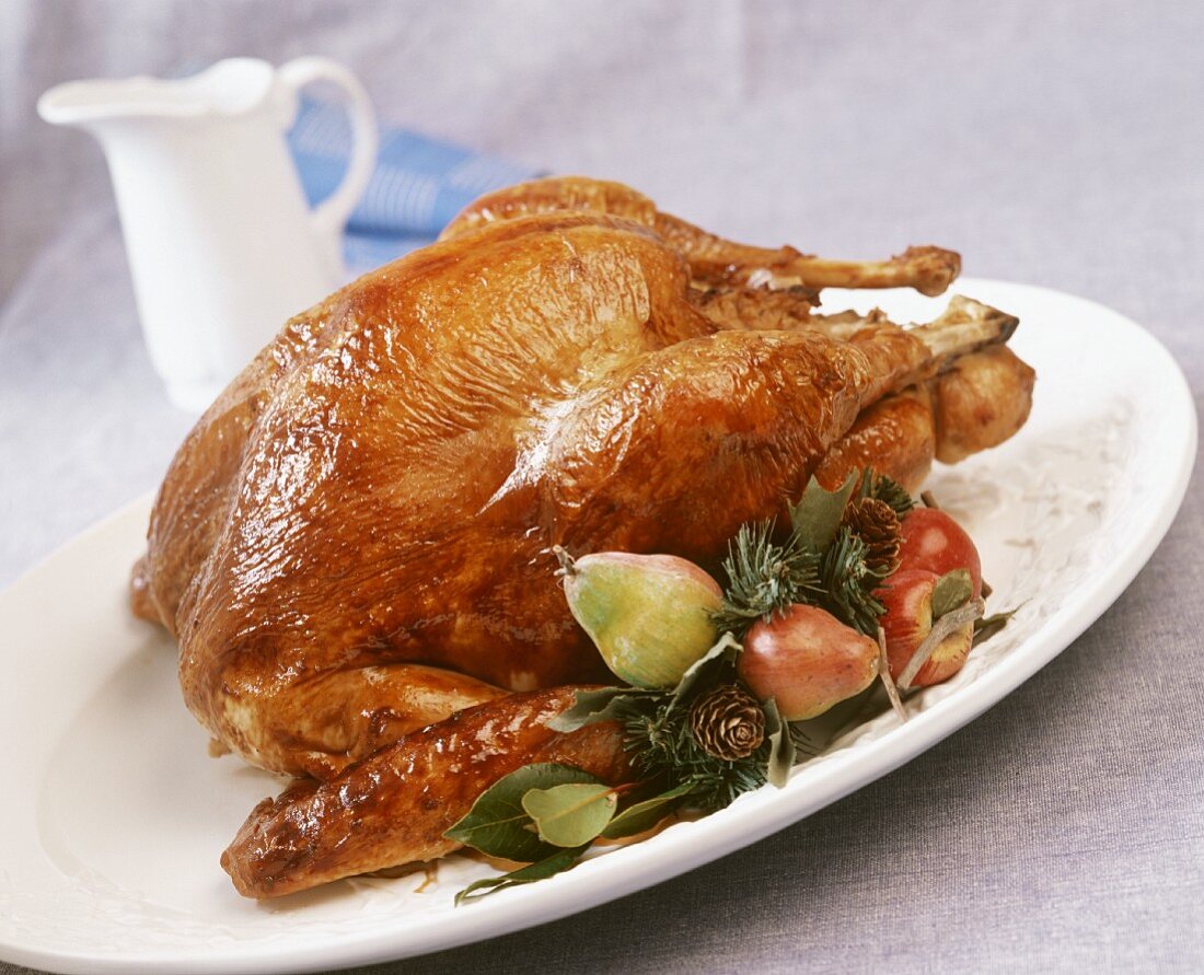 Roast turkey with fruit and pine sprigs on a platter 