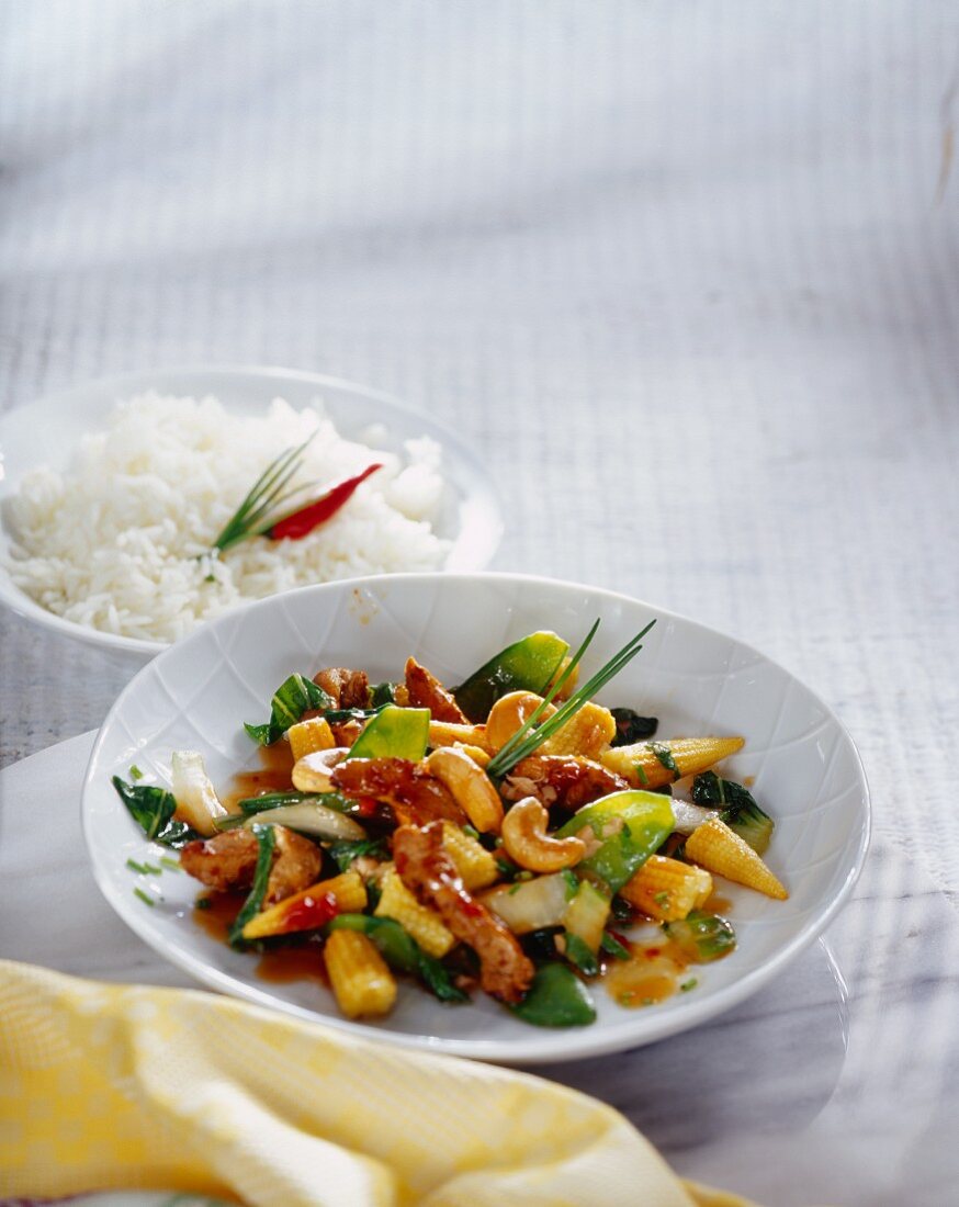 Chicken with vegetables & cashew kernels on plate; rice