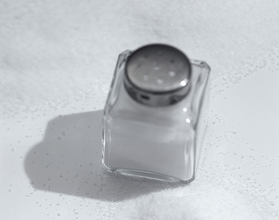 Salz im Salzstreuer und auf weißem Untergrund