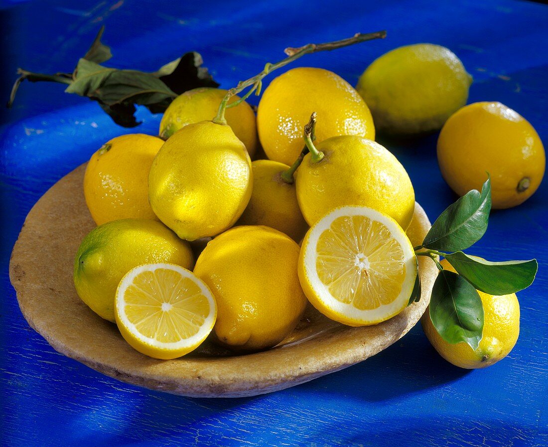 Zitronen, zwei davon halbiert, in einer Schale