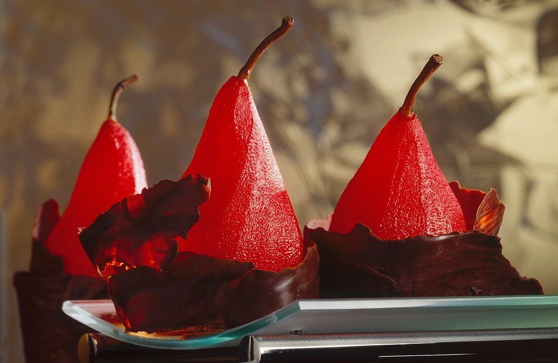 Three poached pears in red wine in chocolate coating