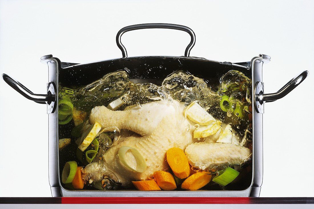 Huhn mit Gemüse in sprudelndem Wasser kochen