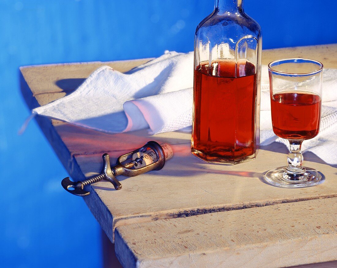 Rotwein in Glas und Flasche auf Holztisch mit Korkenzieher