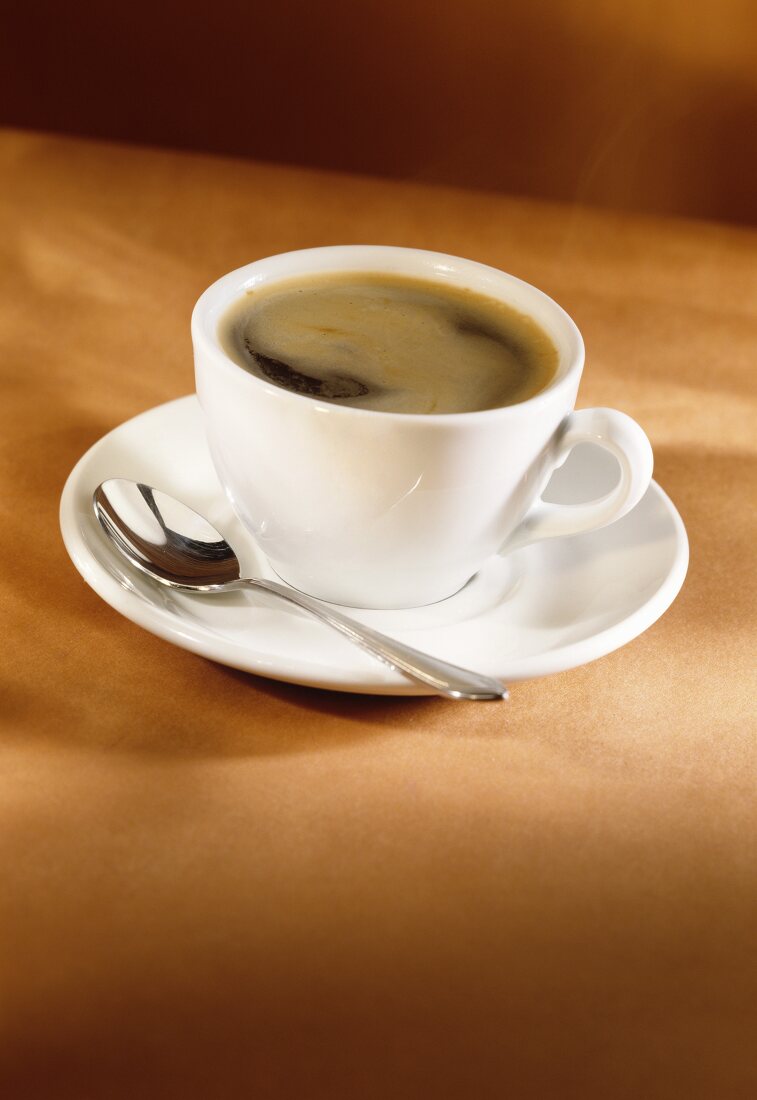 Espresso in weisser Tasse mit Löffel auf Untertasse