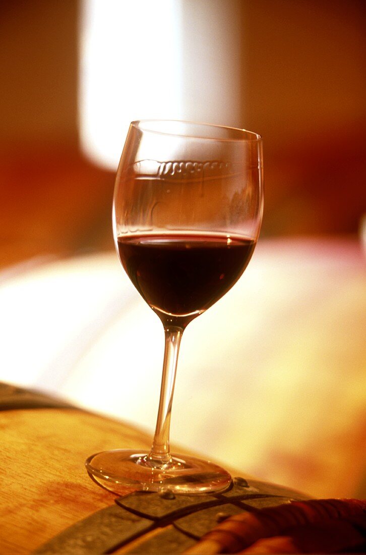 Halb gefülltes Glas Rotwein auf einem Fass