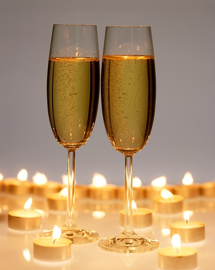 Two champagne glasses surrounded by tea candles