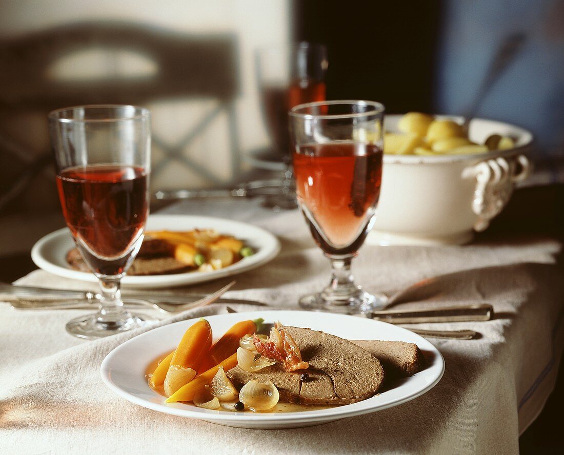 Rinderbraten mit Möhren und Zwiebeln auf Teller; Rotwein