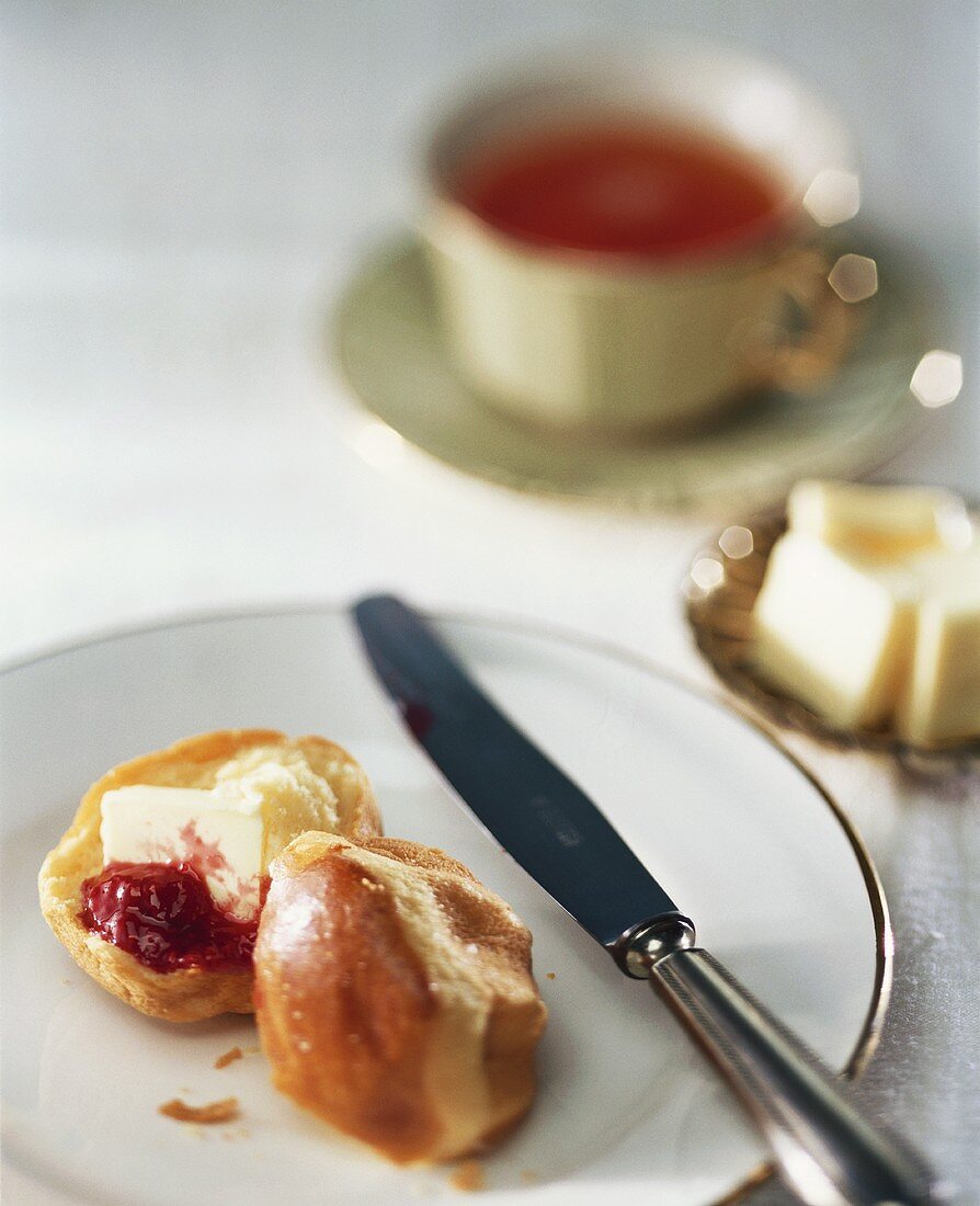 Brioche with butter and jam; Tea cup; Knobs of butter