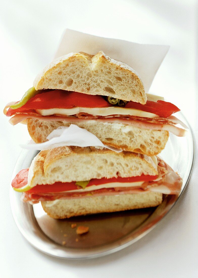 Two ham and cheese sandwiches with peppers on plate