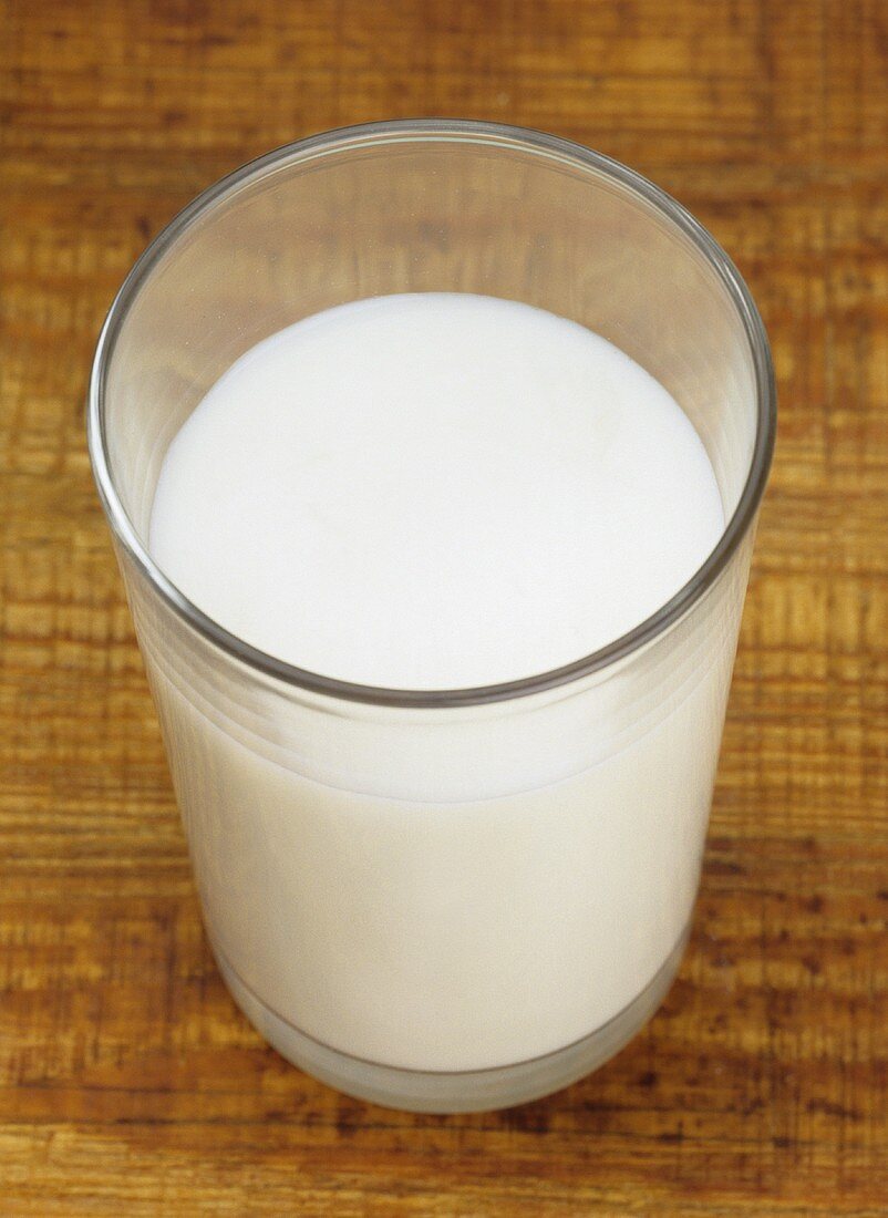 Ein Glas Milch auf braunem Untergrund