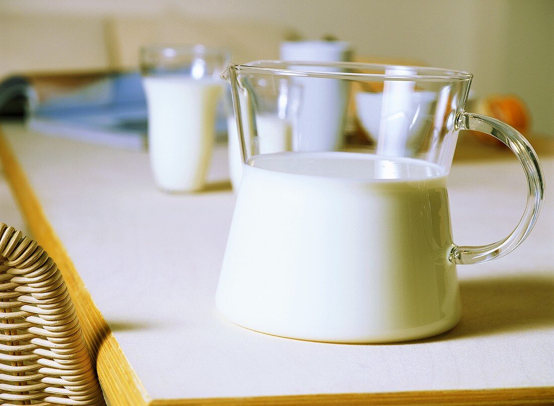 Milch in Glaskrug und Gläsern auf Tisch