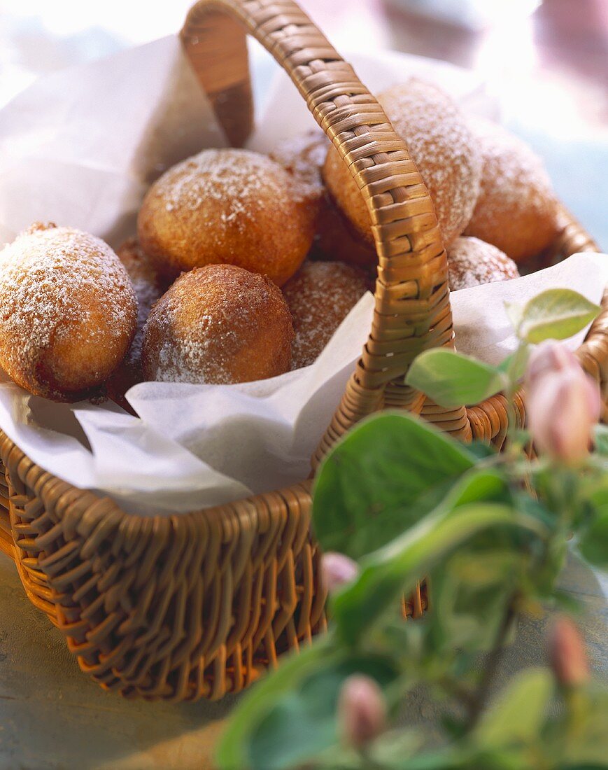 Fritters with icing sugar on paper in a basket