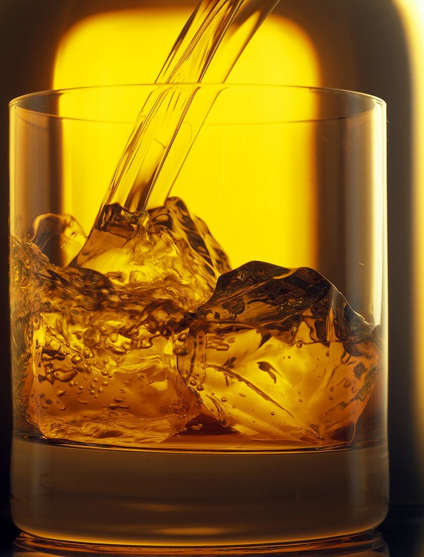 Whiskey in Glas mit Eiswürfeln gießen