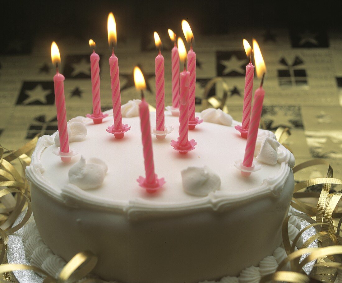 White birthday cake with ten pink candles