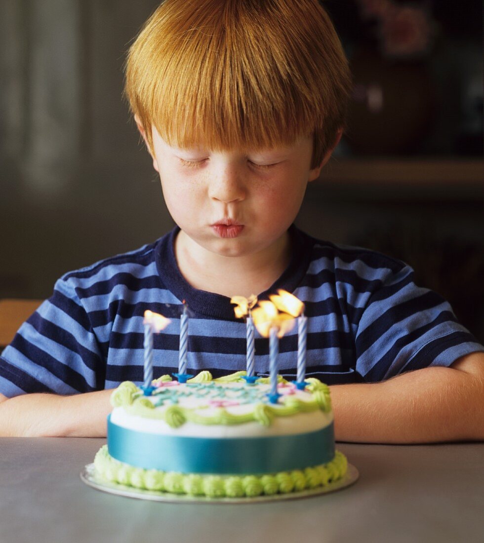 Boy blowing out candles on a birthday cake