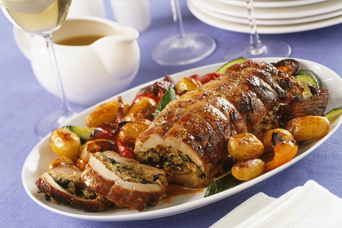 Stuffed pork roll with roast potatoes and vegetables